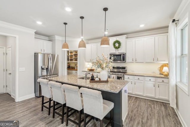 kitchen with white cabinetry, ornamental molding, and stainless steel appliances