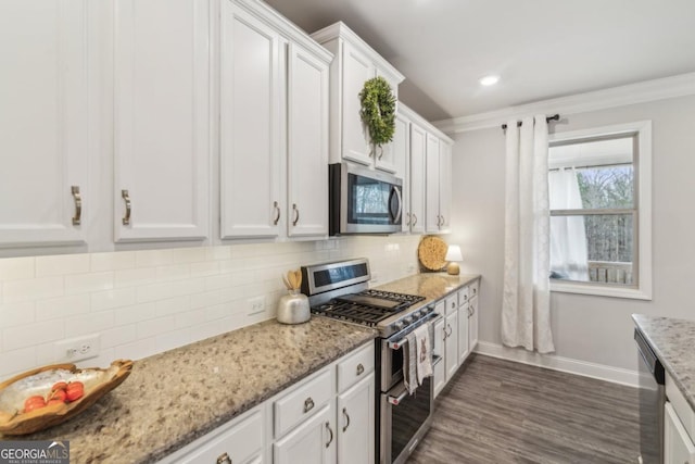 kitchen featuring baseboards, ornamental molding, decorative backsplash, white cabinets, and stainless steel appliances