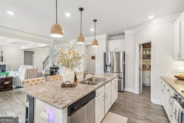 kitchen with a sink, crown molding, white cabinetry, and stainless steel appliances