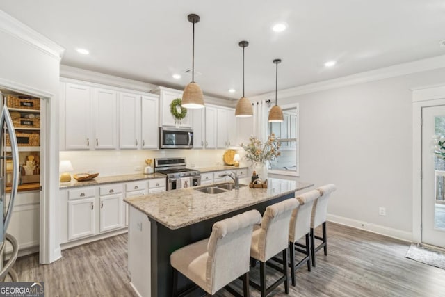 kitchen with a sink, appliances with stainless steel finishes, ornamental molding, and white cabinets