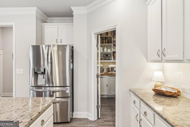 kitchen with wood finished floors, ornamental molding, decorative backsplash, white cabinets, and stainless steel fridge