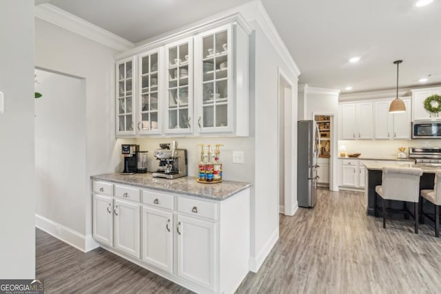 kitchen with light wood finished floors, glass insert cabinets, appliances with stainless steel finishes, white cabinetry, and crown molding