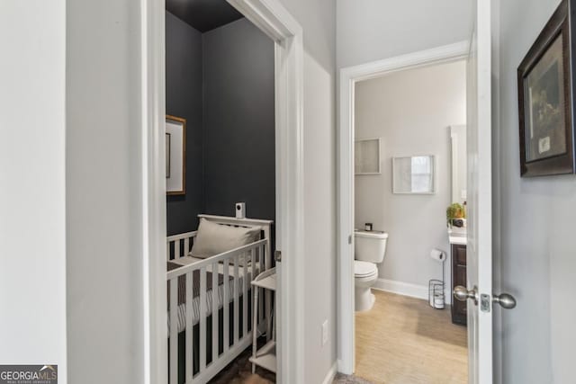 bathroom with toilet, baseboards, and wood finished floors