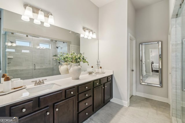 bathroom featuring double vanity, a shower stall, baseboards, and a sink