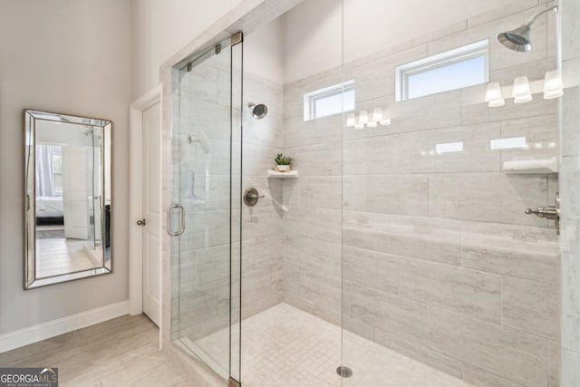 bathroom with a shower stall, baseboards, and connected bathroom