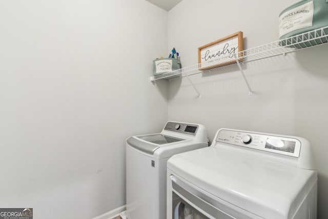 clothes washing area featuring laundry area, baseboards, and washer and clothes dryer