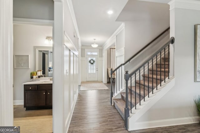 entrance foyer with stairway, wood finished floors, baseboards, and ornamental molding