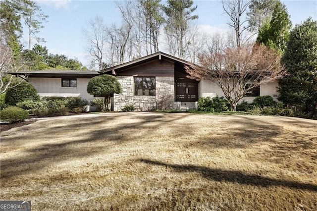 mid-century modern home featuring a front lawn and stone siding