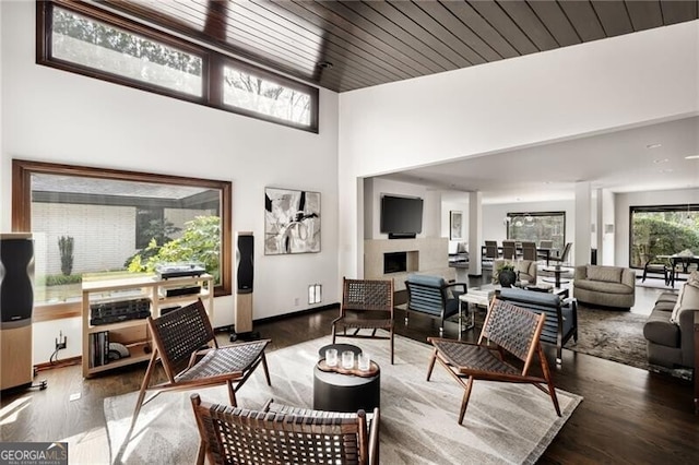 living room with a fireplace, wood ceiling, wood finished floors, and baseboards