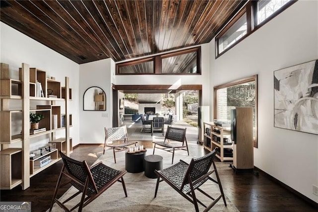 living area featuring baseboards, wood finished floors, wooden ceiling, and a fireplace