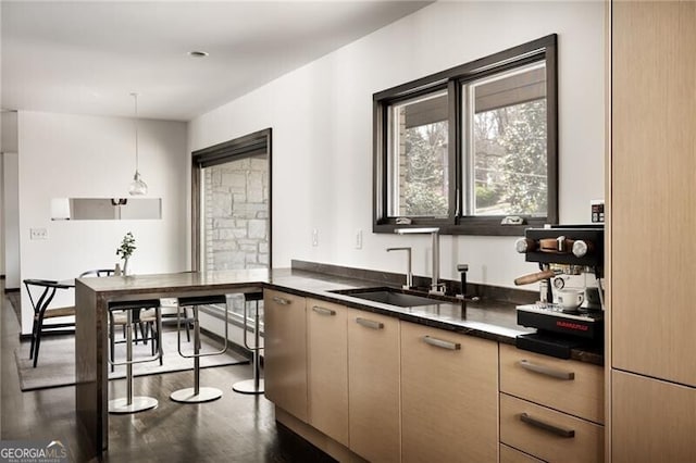 kitchen with modern cabinets, pendant lighting, a sink, dark countertops, and dark wood-style flooring