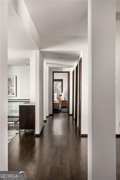 corridor with baseboards and wood finished floors