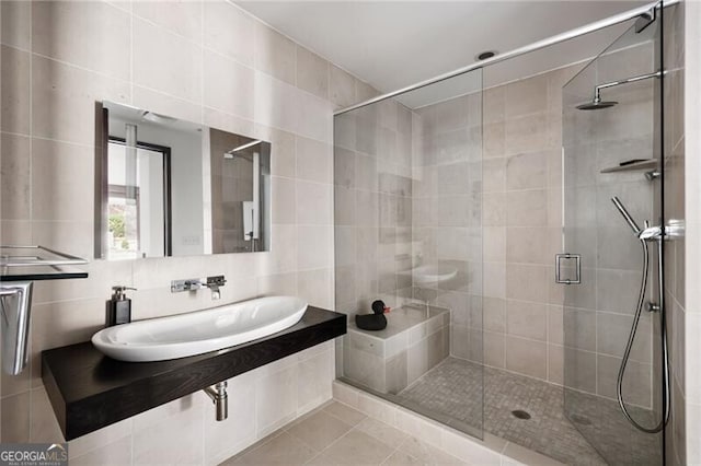 full bathroom featuring a sink, decorative backsplash, a shower stall, tile walls, and tile patterned floors