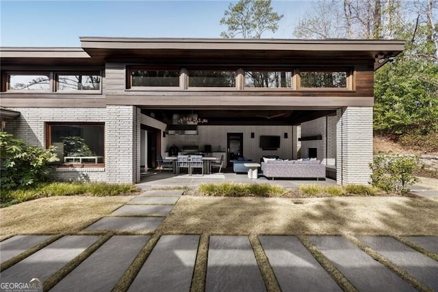 rear view of house featuring a patio, brick siding, and an outdoor hangout area