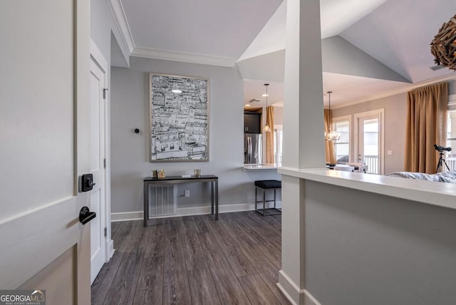 interior space featuring a kitchen bar, ornamental molding, dark wood-style floors, stainless steel fridge with ice dispenser, and vaulted ceiling