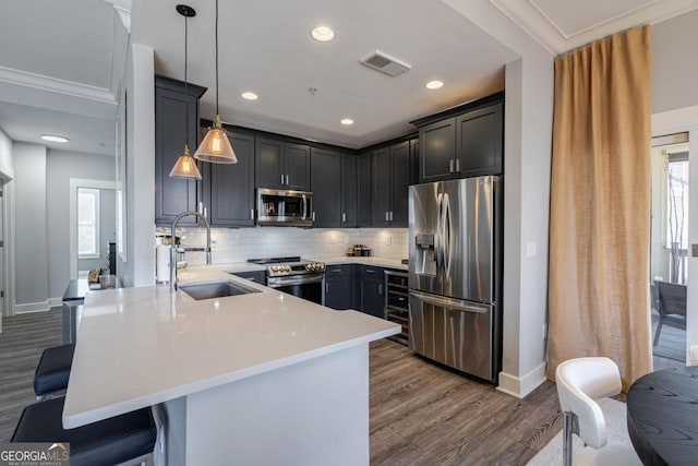 kitchen featuring light countertops, a kitchen breakfast bar, appliances with stainless steel finishes, a peninsula, and a sink