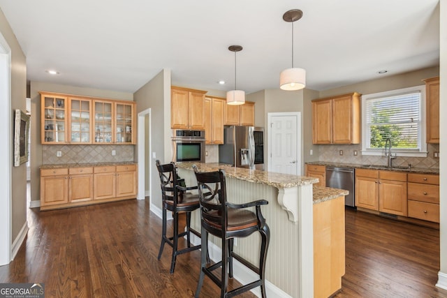 kitchen with dark wood finished floors, appliances with stainless steel finishes, light stone counters, and a sink