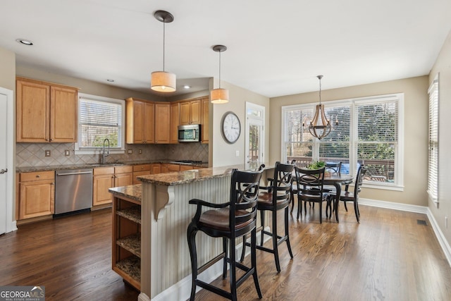 kitchen with dark wood-style flooring, a kitchen breakfast bar, stainless steel appliances, and a sink