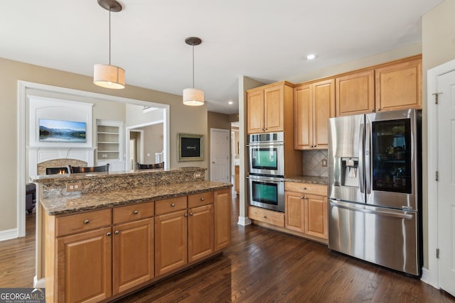 kitchen with dark wood-type flooring, backsplash, appliances with stainless steel finishes, and dark stone counters