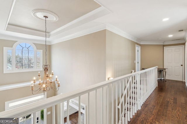 corridor with dark wood finished floors, a raised ceiling, and an upstairs landing