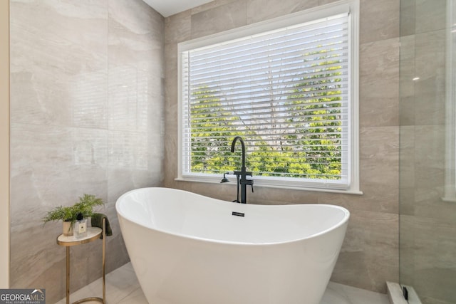 full bath with tile walls and a freestanding tub