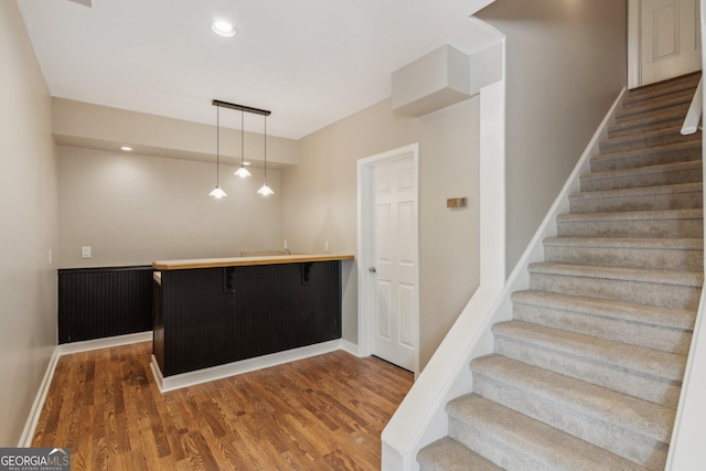 stairway featuring bar area, recessed lighting, wood finished floors, and baseboards