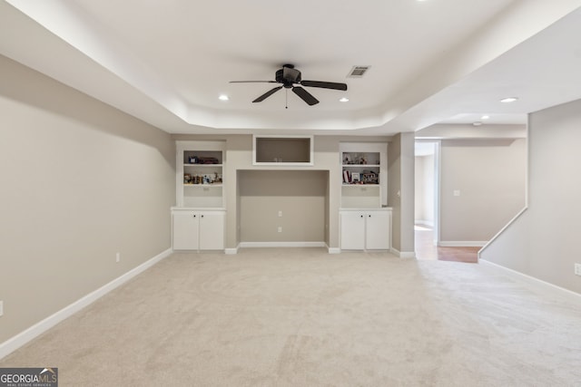 unfurnished living room featuring light carpet, a tray ceiling, recessed lighting, baseboards, and ceiling fan