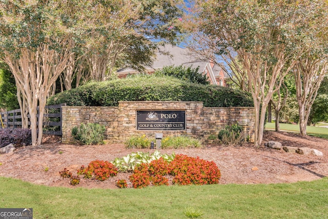 community / neighborhood sign featuring a lawn and fence