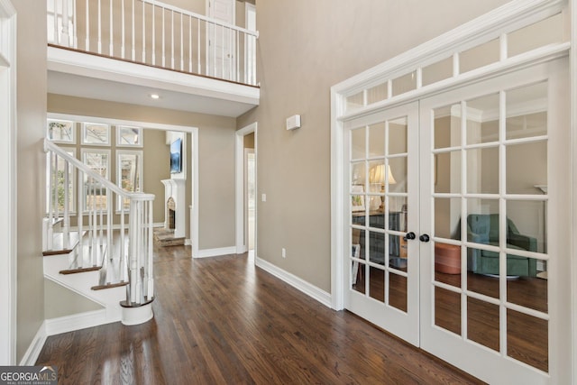 foyer with dark wood finished floors, french doors, stairway, a high ceiling, and baseboards