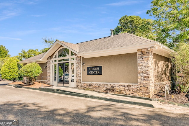 view of front of home featuring stucco siding, stone siding, and roof with shingles