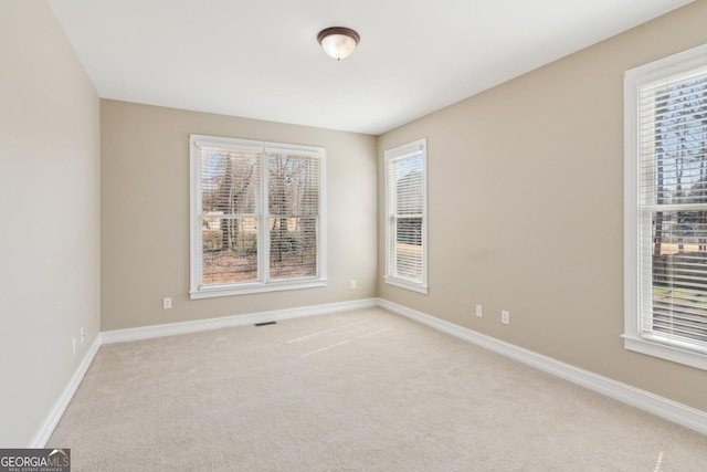 spare room with light carpet, visible vents, a healthy amount of sunlight, and baseboards