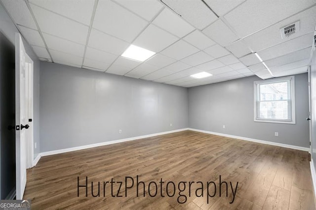 spare room with visible vents, a drop ceiling, baseboards, and wood finished floors