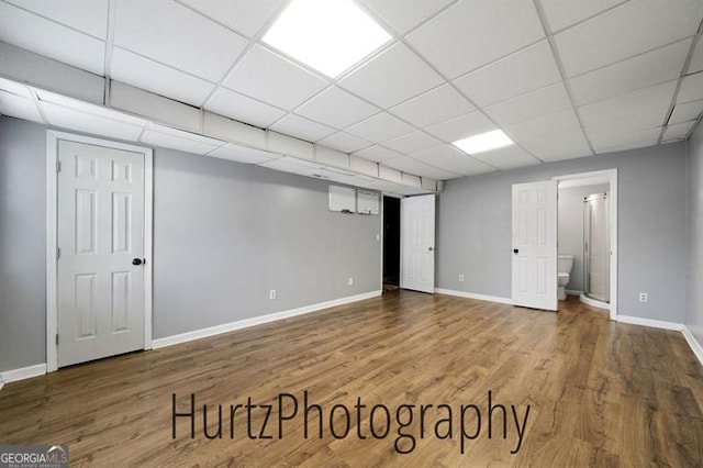 finished below grade area with wood finished floors, baseboards, and a paneled ceiling