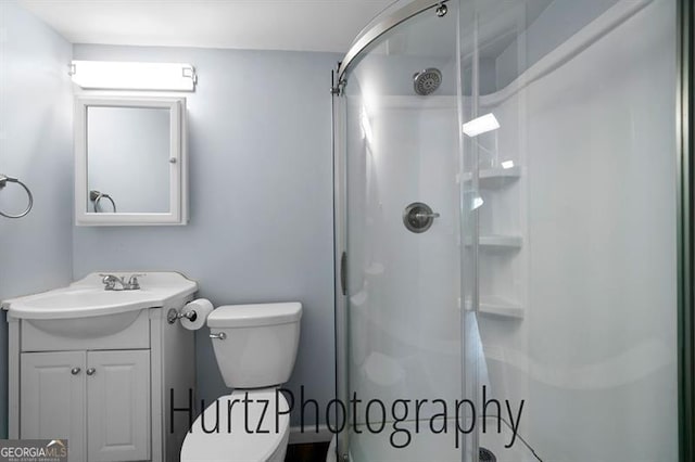 bathroom featuring vanity, toilet, and a stall shower