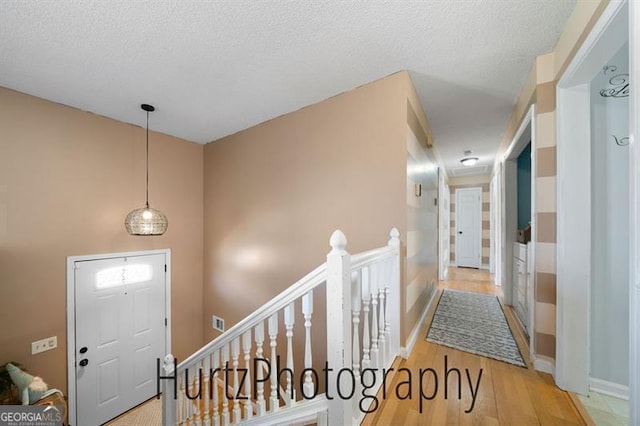 entryway featuring wood finished floors, baseboards, and a textured ceiling