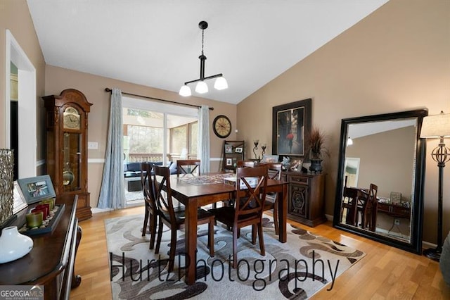 dining area with light wood finished floors and lofted ceiling