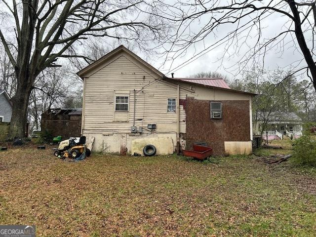 view of side of property with metal roof and a yard