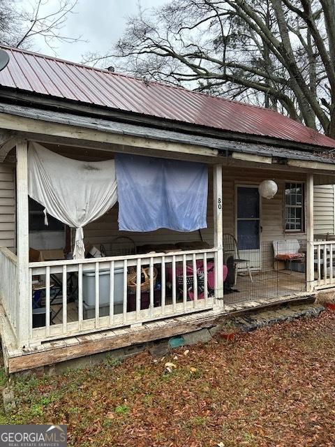 view of property exterior featuring metal roof and a porch