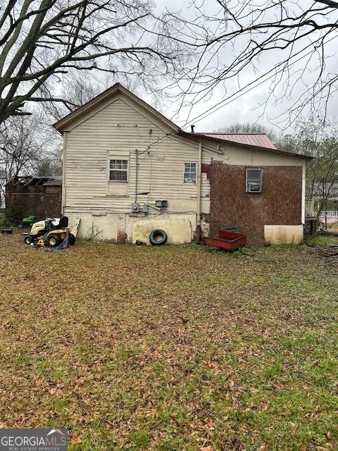 view of side of home with a lawn and metal roof