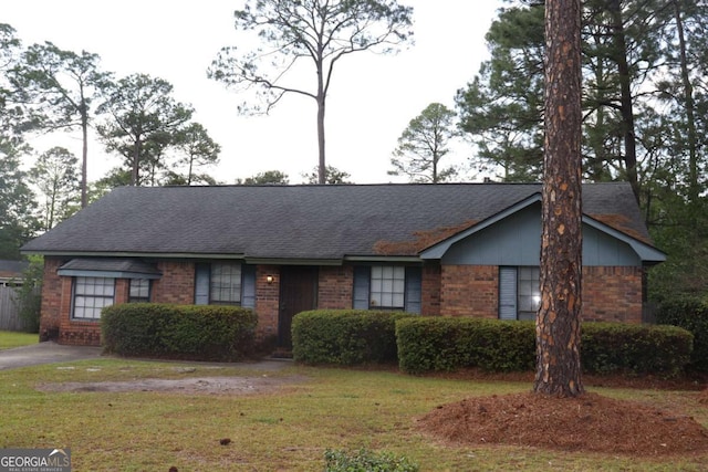 ranch-style house featuring a front lawn, brick siding, and a shingled roof