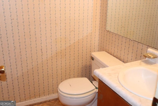 bathroom featuring toilet, vanity, and wallpapered walls