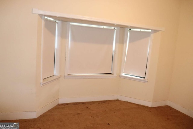 carpeted empty room featuring baseboards