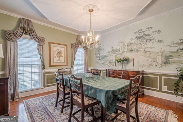 dining room with crown molding, wood finished floors, a wainscoted wall, and a chandelier