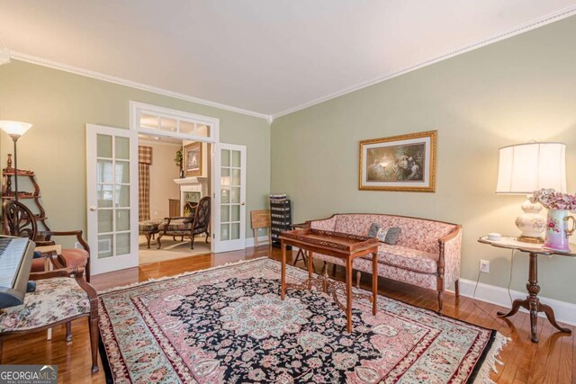 living area with french doors, baseboards, wood finished floors, and ornamental molding