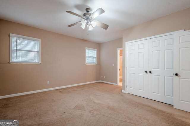 unfurnished bedroom with ceiling fan, baseboards, a closet, and light carpet