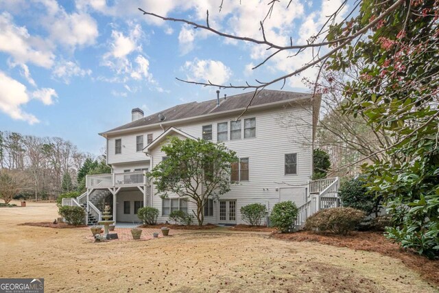 back of property featuring stairway, french doors, and a chimney