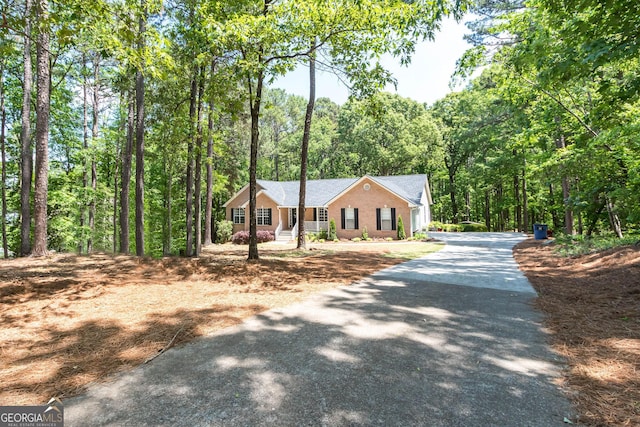 view of front of house with aphalt driveway, a porch, and a forest view