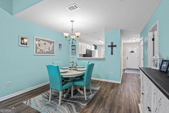 dining room with visible vents, dark wood-type flooring, and a textured ceiling