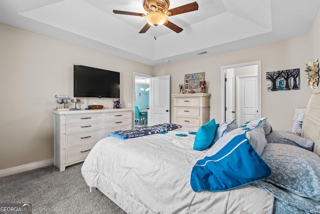 bedroom featuring light colored carpet, baseboards, a tray ceiling, and a ceiling fan