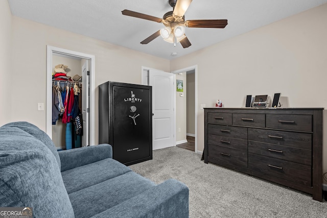 interior space with a walk in closet, light carpet, a ceiling fan, a closet, and baseboards